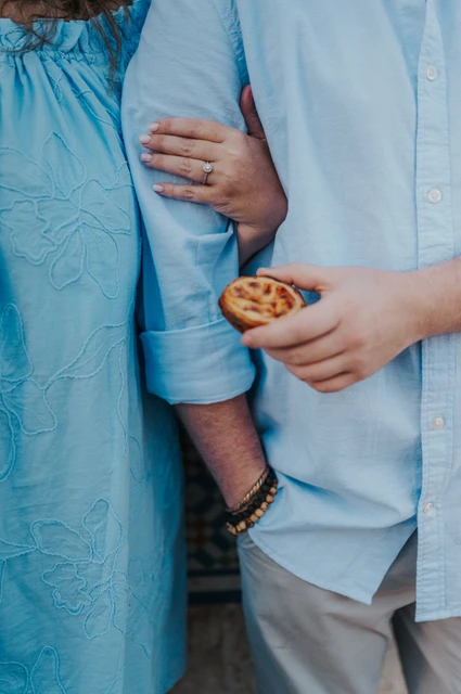 A pastry and engagement ring detail | Lisbon engagement photoshoot A close detail of the couple’s hands, a custard tart and the woman’s engagement ring during their engagement photoshoot in Lisbon.