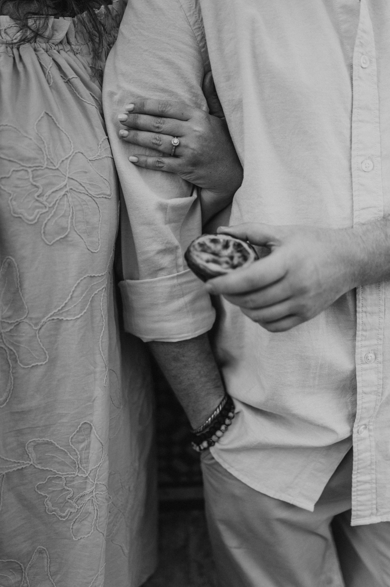Black-and-white photograph: a close detail of the couple’s hands, a custard tart and the woman’s engagement ring during their engagement photoshoot in Lisbon.