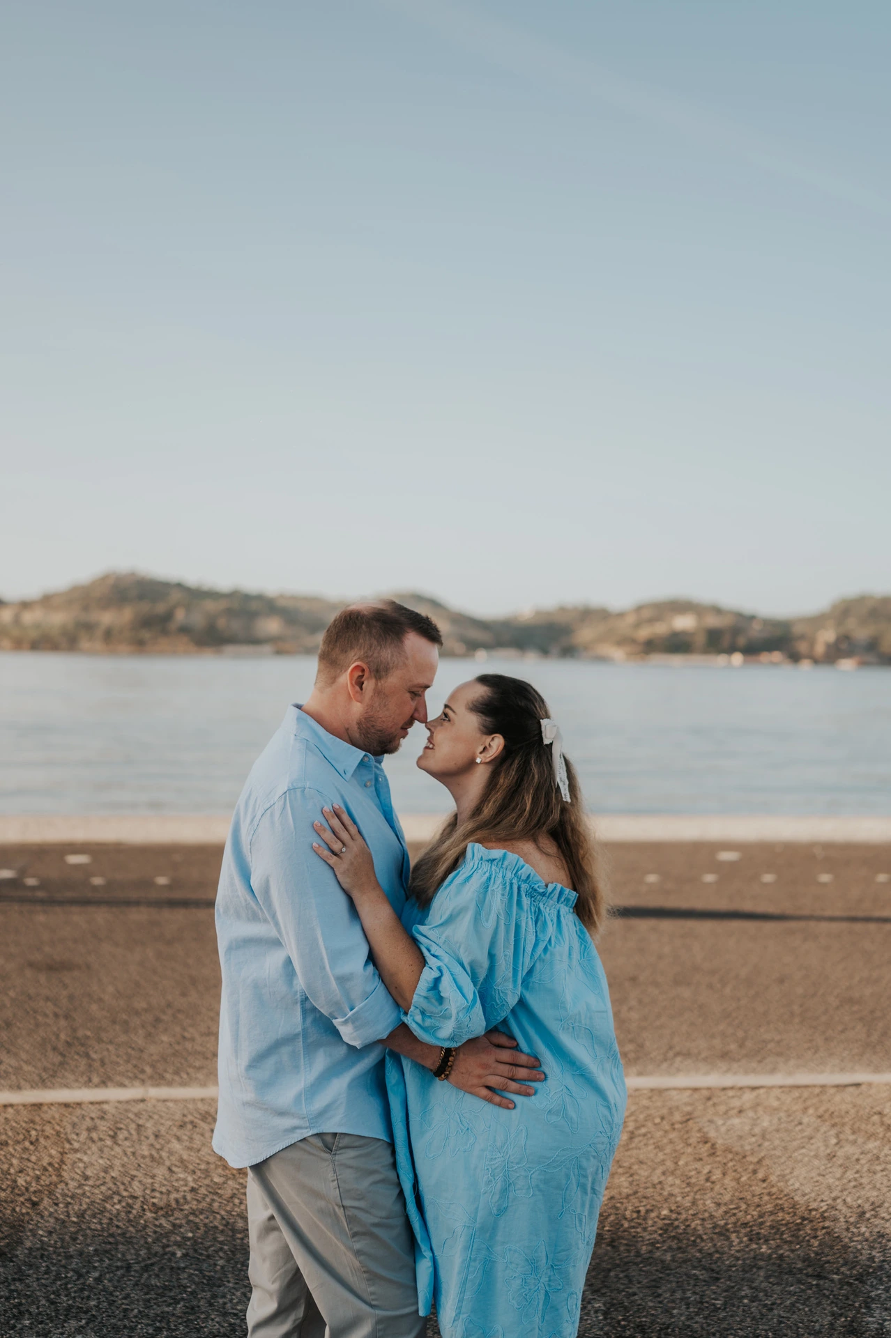 The couple holding each other face to face beside the river during their engagement photoshoot in Lisbon.