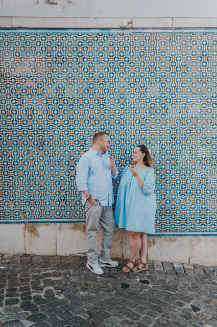 Pastries beside the patterned tiles | Lisbon engagement photoshoot The couple smiling together with pastries in front of a blue and yellow patterned tile wall during their engagement photoshoot in Lisbon.