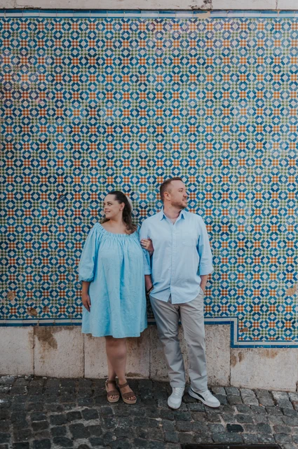 Pastries beside the patterned tiles | Lisbon engagement photoshoot The couple smiling together with pastries in front of a blue and yellow patterned tile wall during their engagement photoshoot in Lisbon.