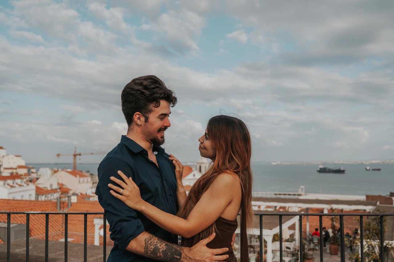 A close embrace above the river | Lisbon engagement photoshoot The couple looking at one another in a close embrace with the river behind them at Portas do Sol during their engagement photoshoot in Lisbon.