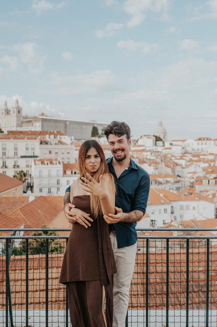A portrait together above the city | Lisbon engagement photoshoot The couple facing the camera with his arms around her at Portas do Sol during their engagement photoshoot in Lisbon.