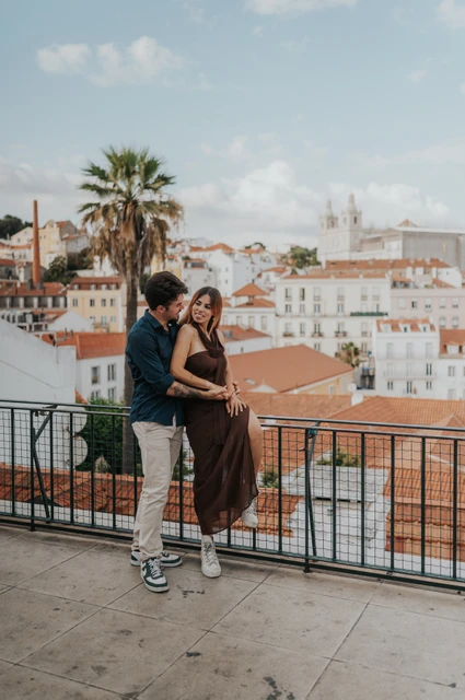 A close embrace by the viewpoint railing | Lisbon engagement photoshoot The couple leaning close together by the Portas do Sol railing during their engagement photoshoot in Lisbon.