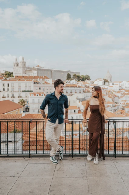 A full-length portrait at the viewpoint | Lisbon engagement photoshoot A full-length portrait of the couple leaning against the Portas do Sol railing during their engagement photoshoot in Lisbon.