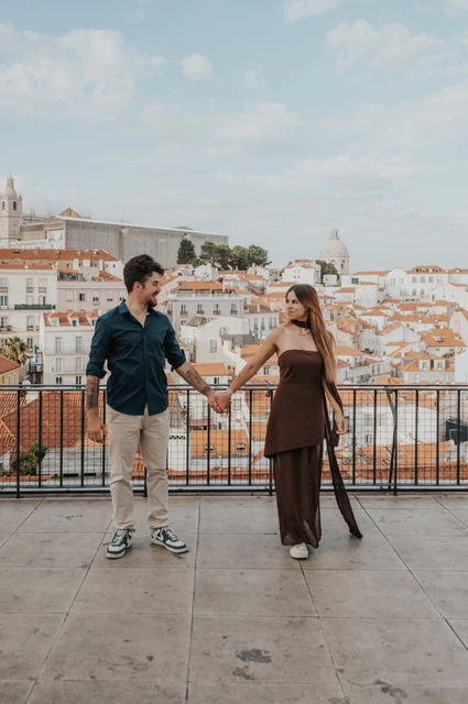Stepping apart with hands joined | Lisbon engagement photoshoot The couple stepping apart while holding hands at Portas do Sol during their engagement photoshoot in Lisbon.