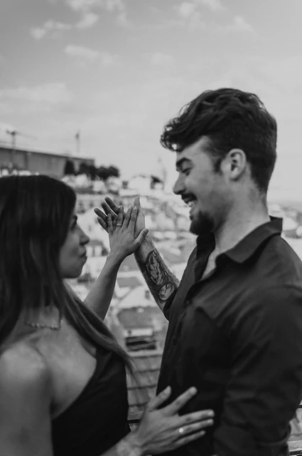 Joined palms in black and white | Lisbon engagement photoshoot A black-and-white close view of the couple lifting their hands together at Portas do Sol during their engagement photoshoot in Lisbon.