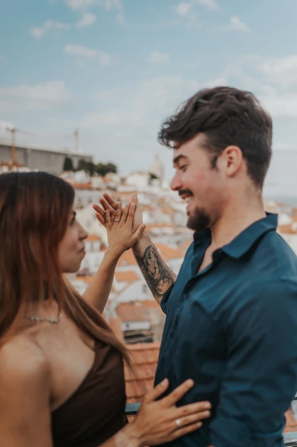 A close view of the couple lifting their hands together with the skyline behind them at Portas do Sol during their engagement photoshoot in Lisbon.