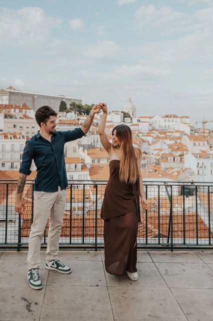 Joined hands before a twirl | Lisbon engagement photoshoot The couple raising their joined hands to begin a turn at Portas do Sol during their engagement photoshoot in Lisbon.