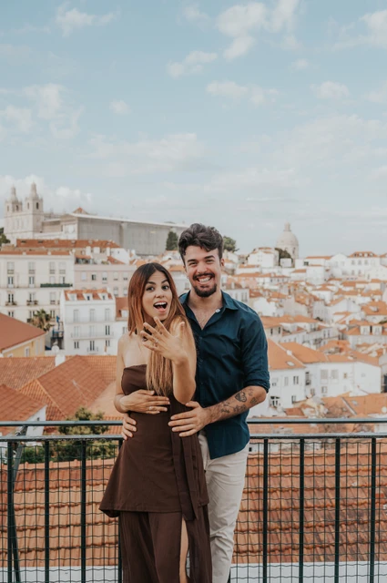 Showing the ring at Portas do Sol | Lisbon engagement photoshoot A full-length portrait of the smiling couple showing her engagement ring at Portas do Sol during their engagement photoshoot in Lisbon.