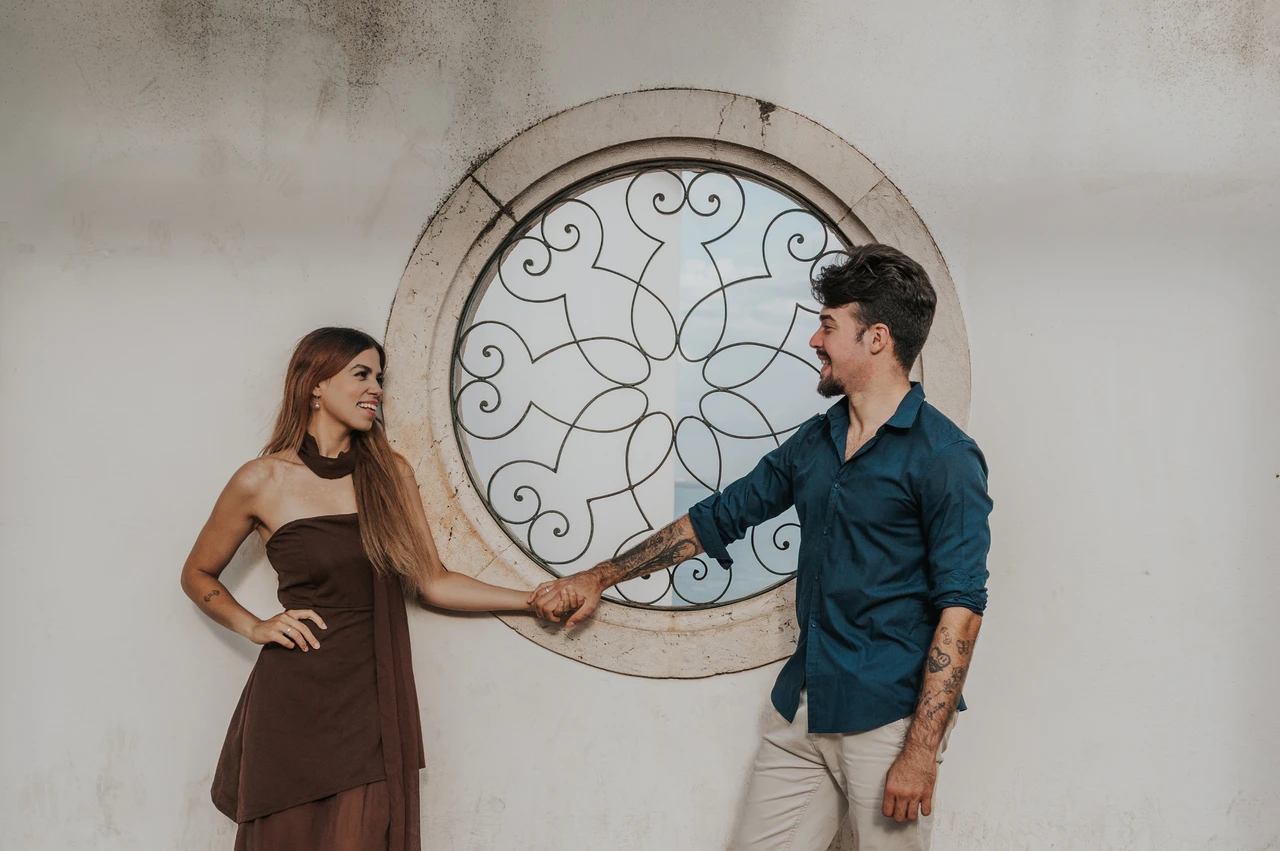 Holding hands beside a circular window | Lisbon engagement photoshoot The couple holding hands in front of a circular window at Santa Luzia during their engagement photoshoot in Lisbon.