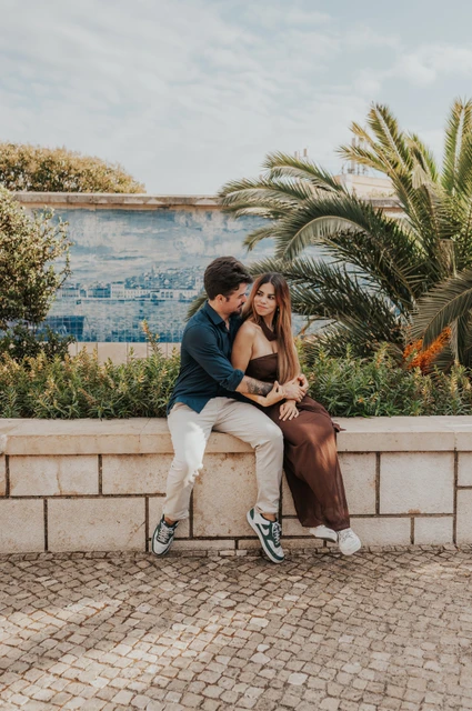 A cheek kiss on the Santa Luzia wall | Lisbon engagement photoshoot A cheek kiss while the couple sit on the garden wall at Santa Luzia during their engagement photoshoot in Lisbon.