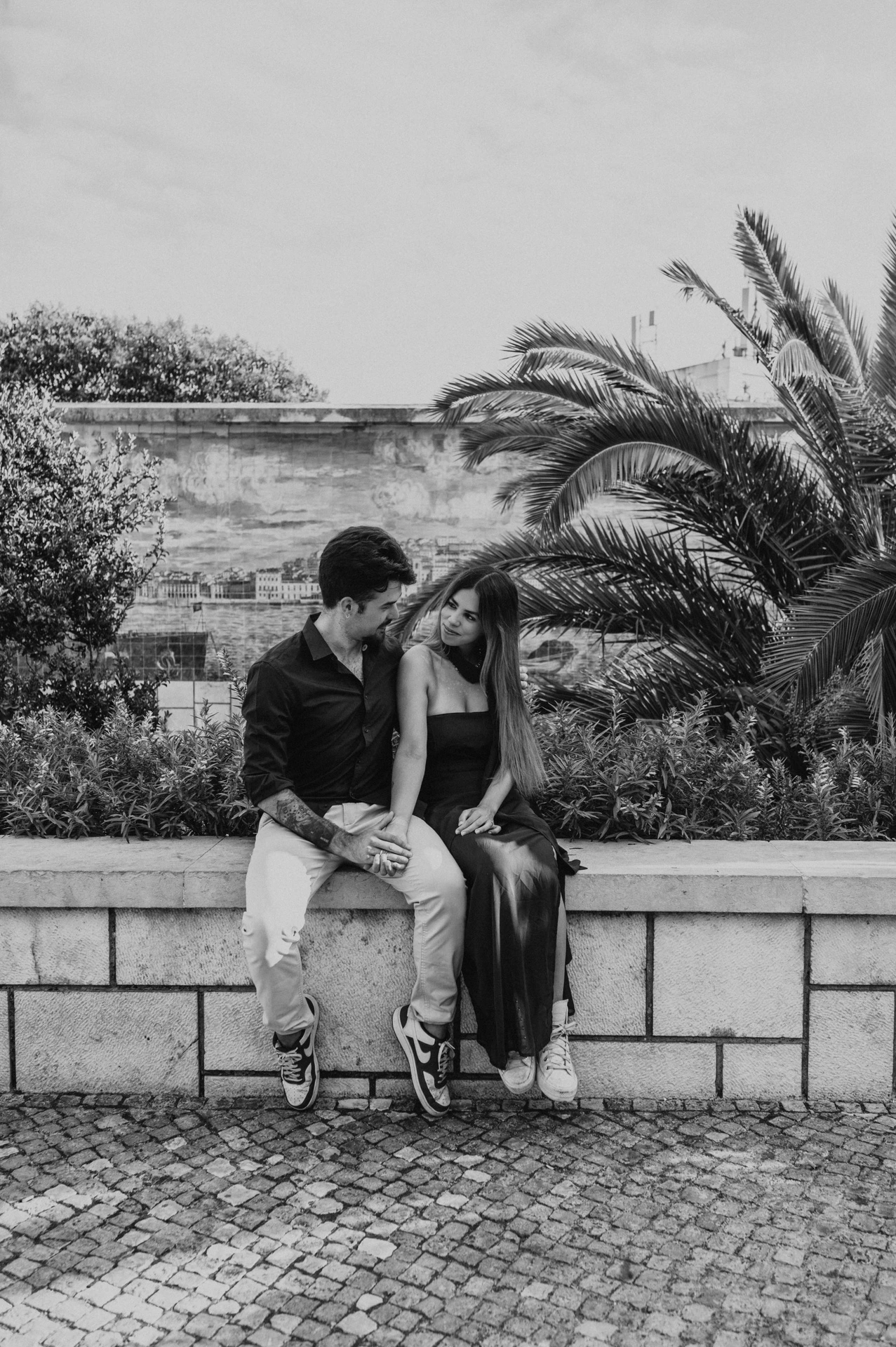 A black-and-white photograph of a forehead kiss on the garden wall at Santa Luzia during their engagement photoshoot in Lisbon.