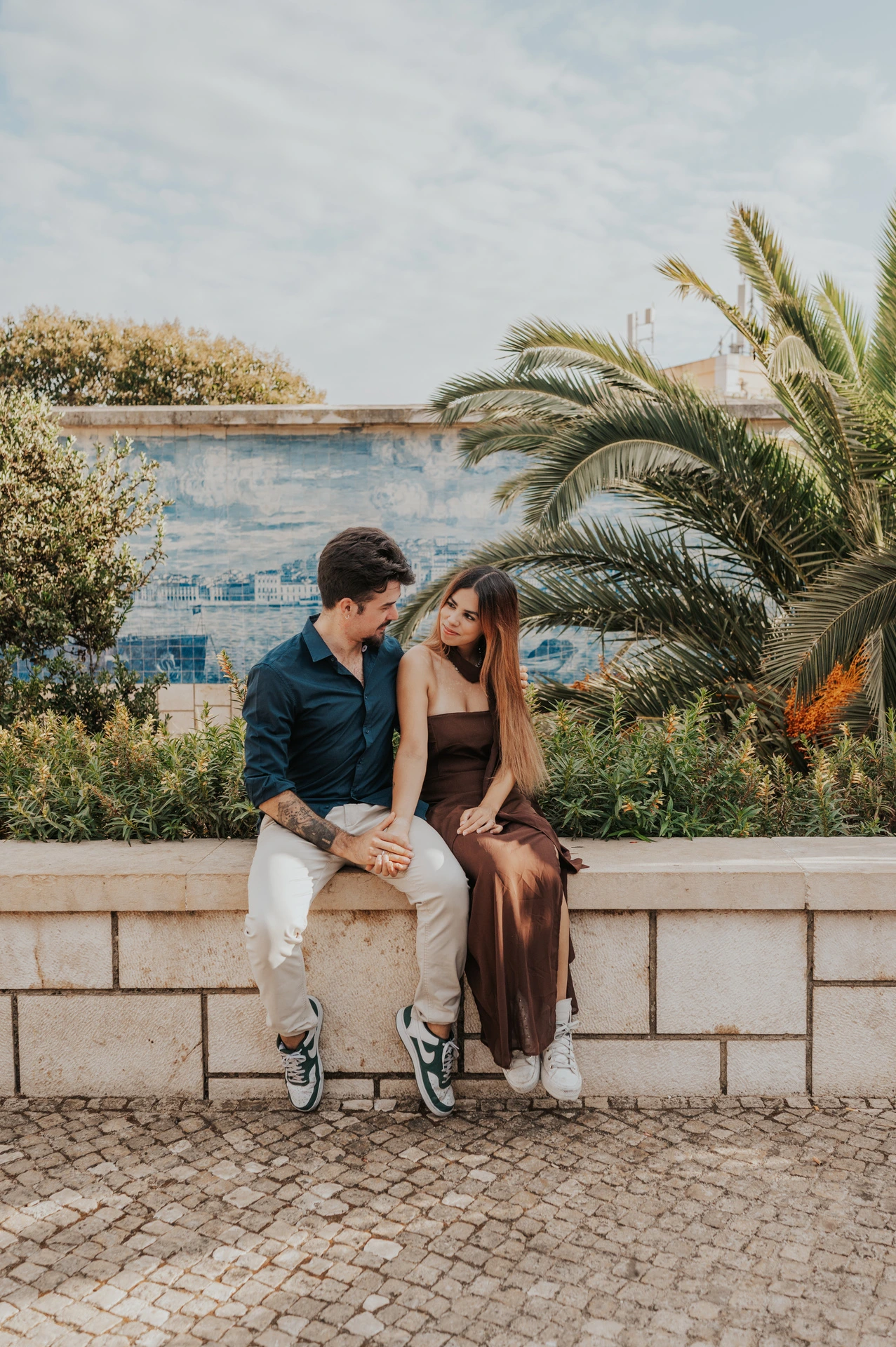 A forehead kiss as the couple sit beside the blue tiled wall at Santa Luzia during their engagement photoshoot in Lisbon.