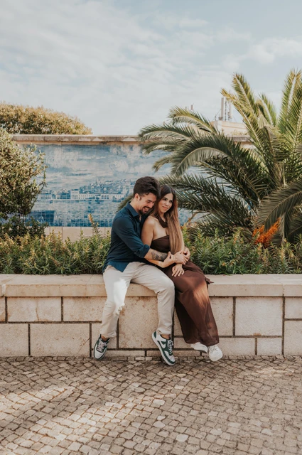 Leaning together beside the blue tiles | Lisbon engagement photoshoot The couple leaning together while seated in front of blue tiles and palms at Santa Luzia during their engagement photoshoot in Lisbon.