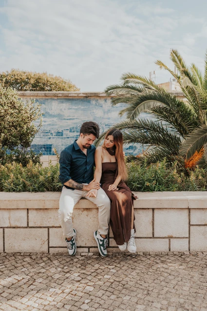 Looking down at their joined hands | Lisbon engagement photoshoot The seated couple looking down at their joined hands at Santa Luzia during their engagement photoshoot in Lisbon.