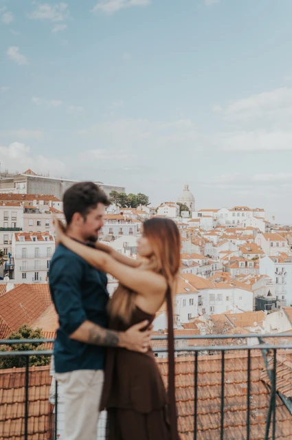 A softly focused rooftop embrace | Lisbon engagement photoshoot A softly focused vertical portrait of the couple embracing at Portas do Sol during their engagement photoshoot in Lisbon.