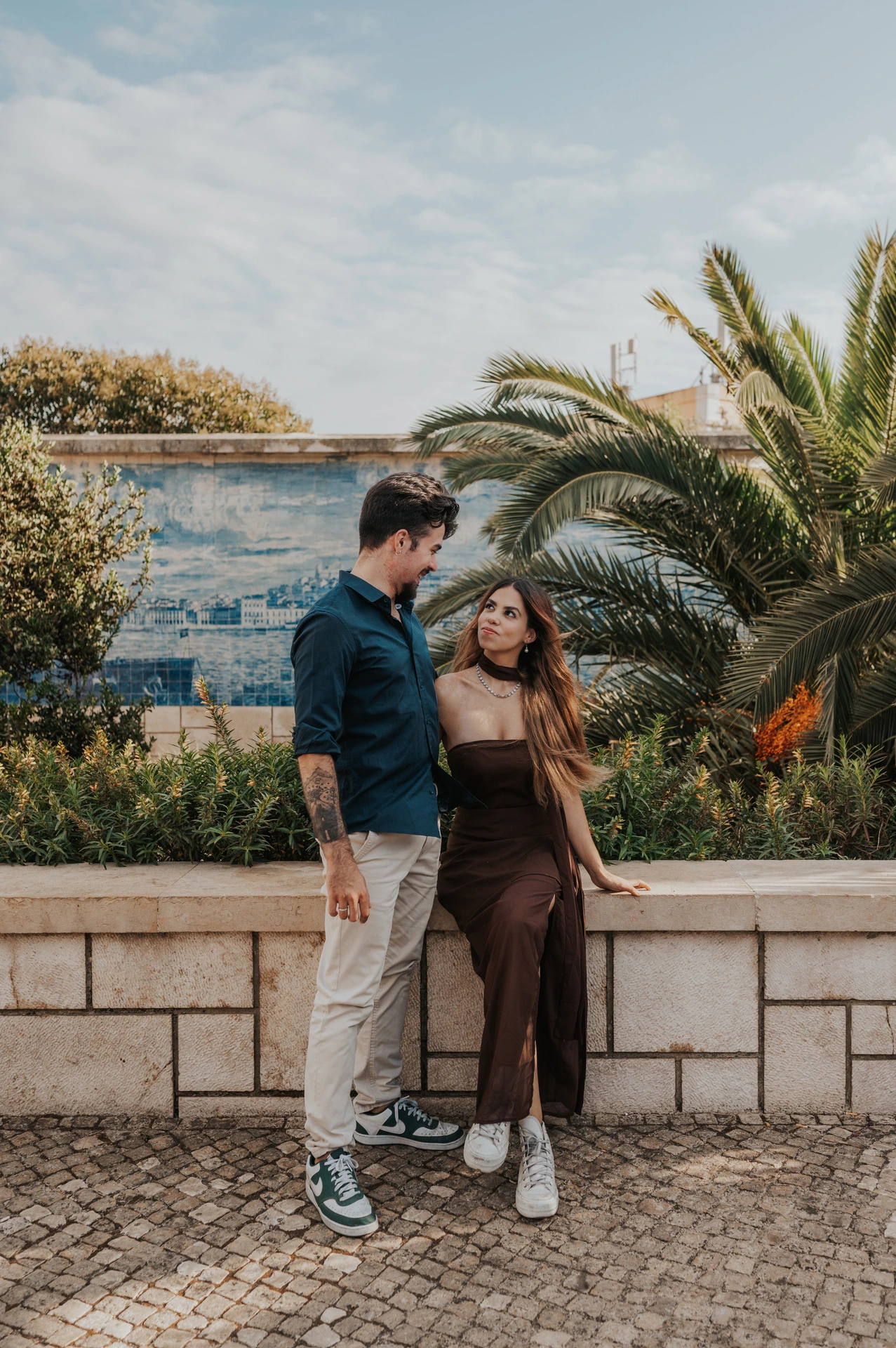 The couple standing beside the low garden wall at Miradouro de Santa Luzia during their engagement photoshoot in Lisbon.