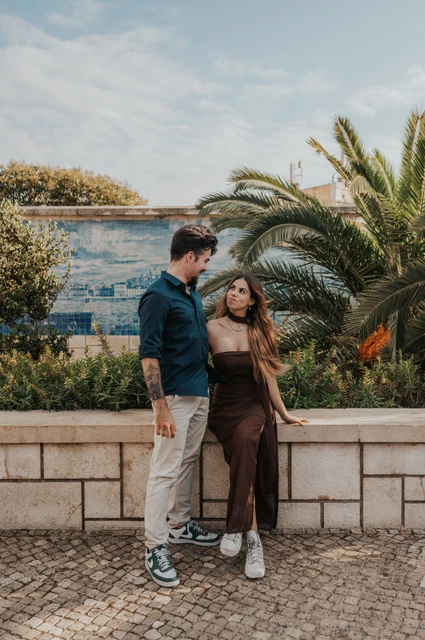 Standing beside the Santa Luzia garden wall | Lisbon engagement photoshoot The couple standing beside the low garden wall at Miradouro de Santa Luzia during their engagement photoshoot in Lisbon.