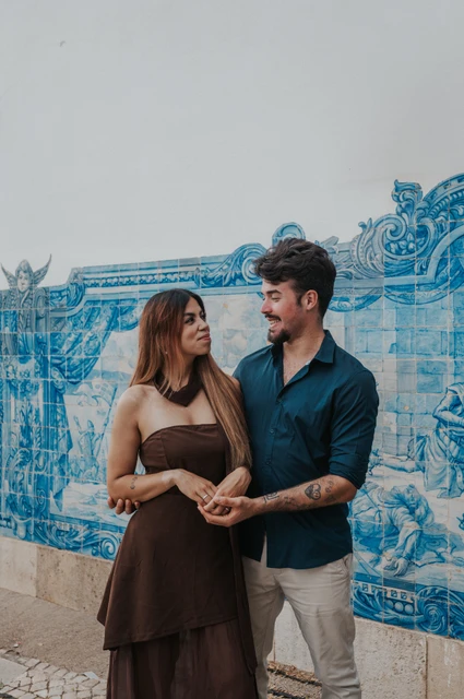 A vertical portrait at the tile wall | Lisbon engagement photoshoot A vertical portrait of the couple holding hands beside the blue-and-white tile wall at Santa Luzia during their engagement photoshoot in Lisbon.