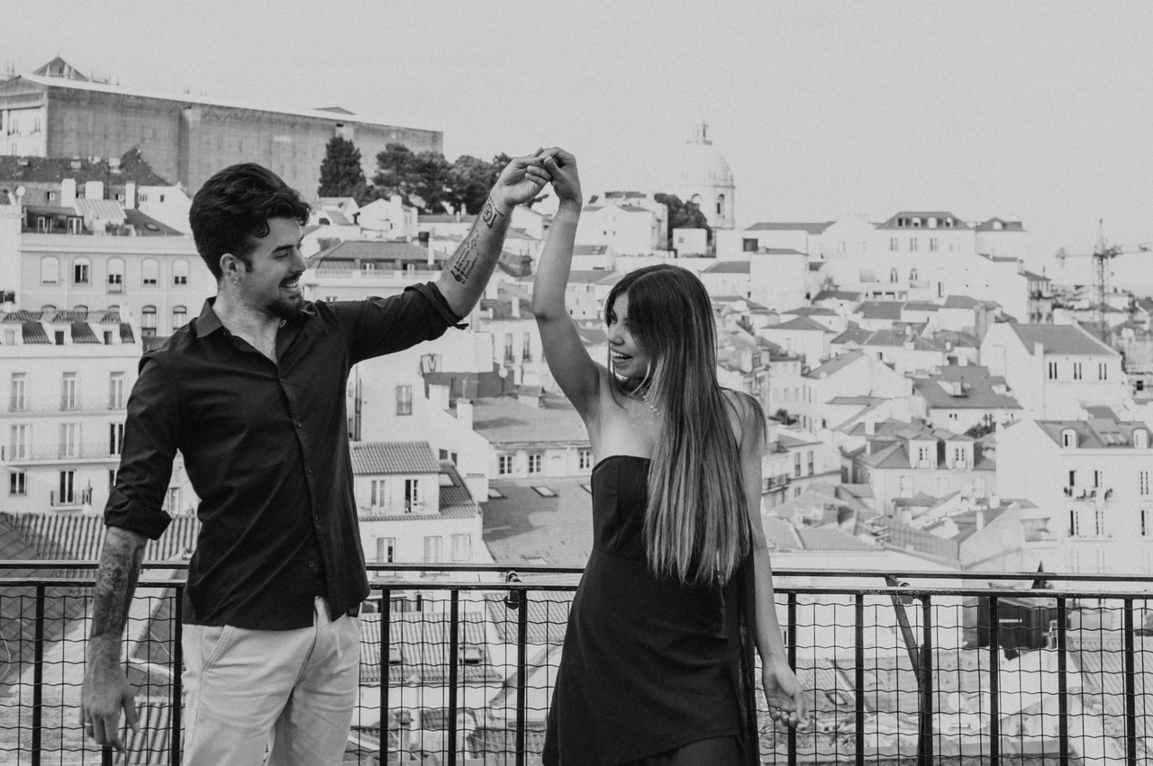 A rooftop twirl in black and white | Lisbon engagement photoshoot A black-and-white photograph of the couple turning together at Portas do Sol during their engagement photoshoot in Lisbon.