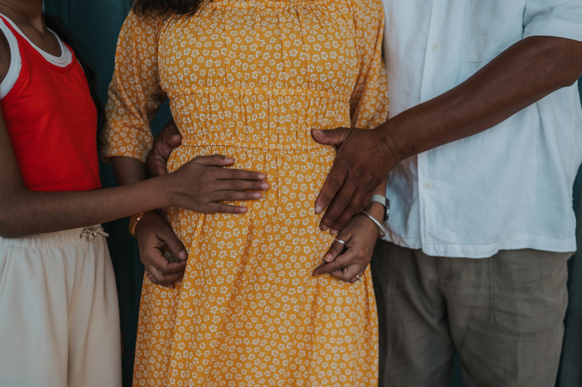 A close detail of the family’s hands resting together on the mother’s belly during their family and maternity photoshoot in Lisbon.