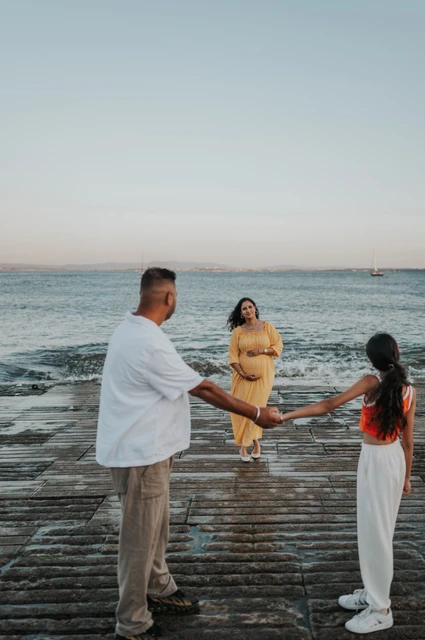 Family hands joined at the waterfront | Lisbon family and maternity photoshoot The father and daughter holding hands with the expectant mother beside the river during their family and maternity photoshoot in Lisbon.