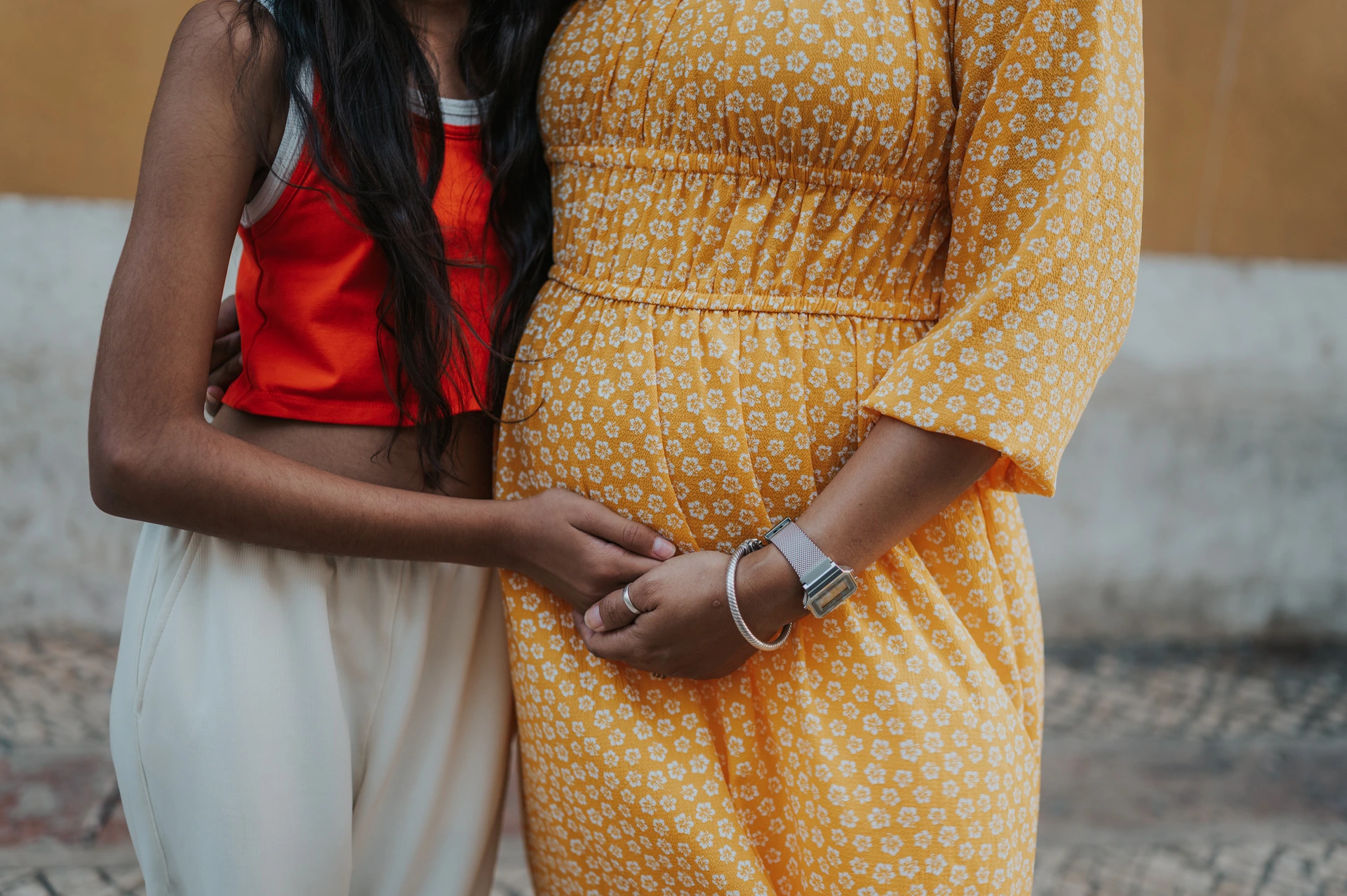 Mother and daughter holding hands | Lisbon family and maternity photoshoot A close detail of the mother and daughter holding hands over the yellow dress during their family and maternity photoshoot in Lisbon.