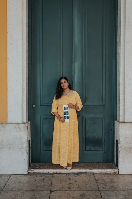 Ultrasound photographs held at the doorway | Lisbon family and maternity photoshoot The expectant mother holding a strip of ultrasound photographs in front of the green door during their family and maternity photoshoot in Lisbon.