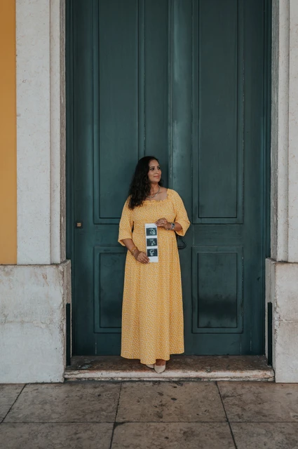 Ultrasound photographs held at the doorway | Lisbon family and maternity photoshoot The expectant mother holding a strip of ultrasound photographs in front of the green door during their family and maternity photoshoot in Lisbon.