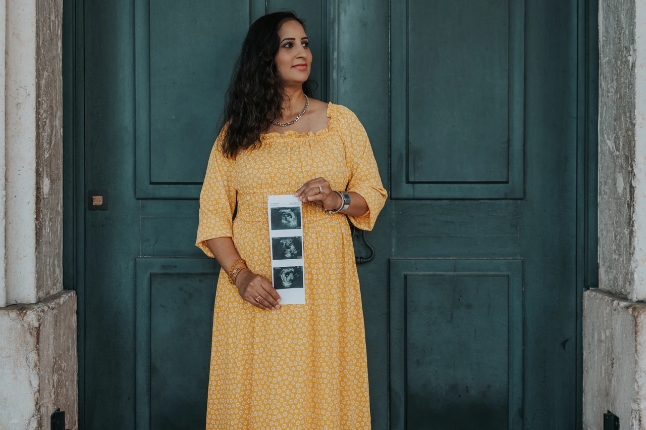 Ultrasound photographs held at the doorway | Lisbon family and maternity photoshoot The expectant mother holding a strip of ultrasound photographs in front of the green door during their family and maternity photoshoot in Lisbon.