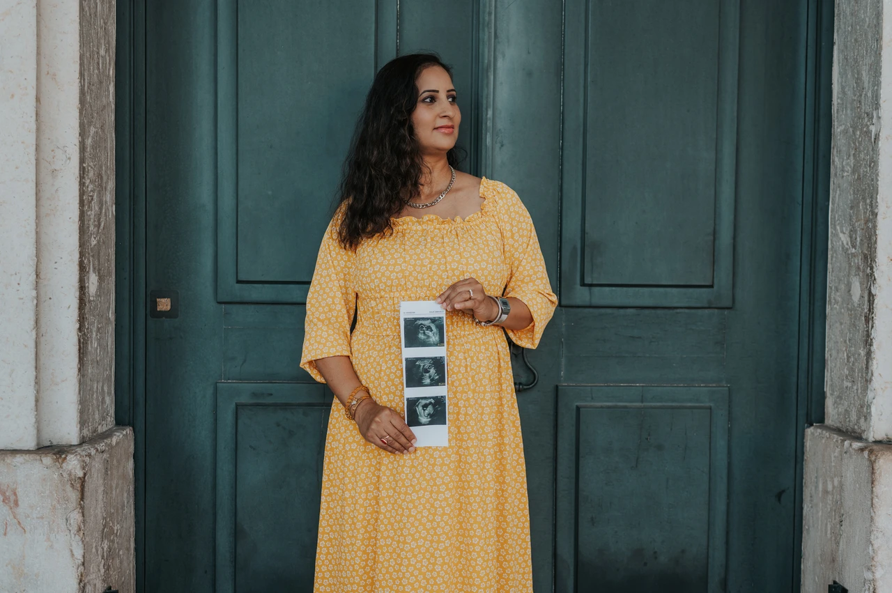 Ultrasound photographs held at the doorway | Lisbon family and maternity photoshoot The expectant mother holding a strip of ultrasound photographs in front of the green door during their family and maternity photoshoot in Lisbon.