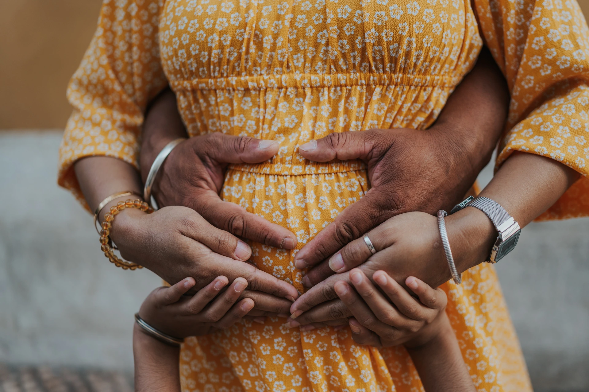 A close detail of the parents’ hands resting together on the mother’s belly during their family and maternity photoshoot in Lisbon.