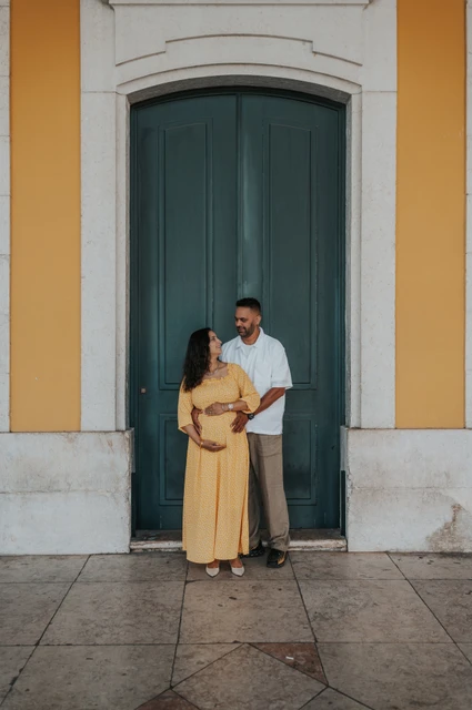 An embrace beside the green doorway | Lisbon family and maternity photoshoot The expectant parents standing together in an embrace beside the green door during their family and maternity photoshoot in Lisbon.