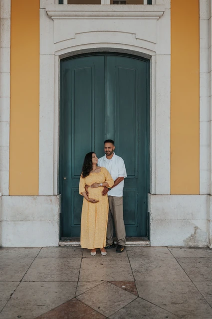 An embrace beside the green doorway | Lisbon family and maternity photoshoot The expectant parents standing together in an embrace beside the green door during their family and maternity photoshoot in Lisbon.