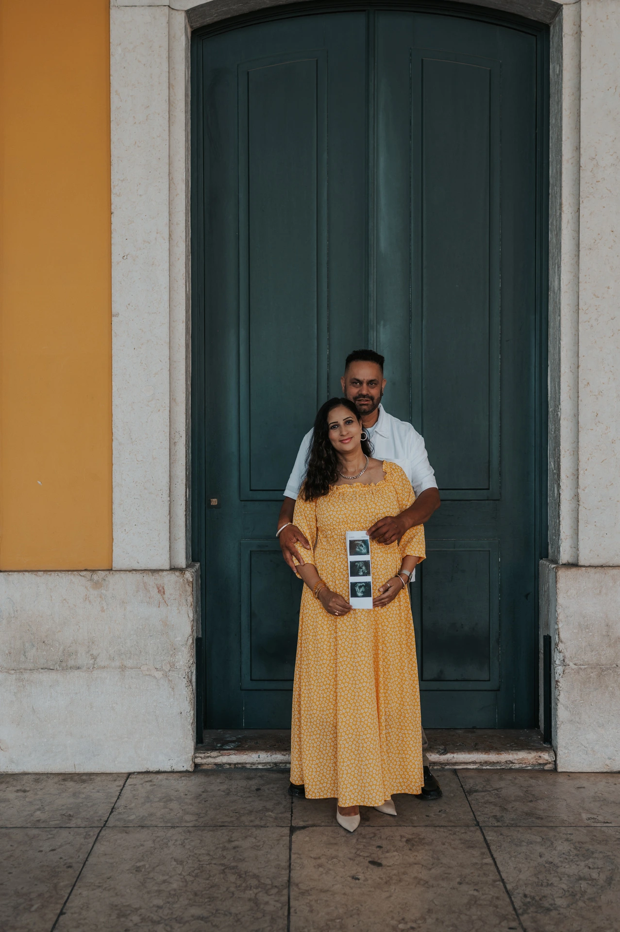 The expectant parents standing close together with the ultrasound photographs in the mother’s hands during their family and maternity photoshoot in Lisbon.