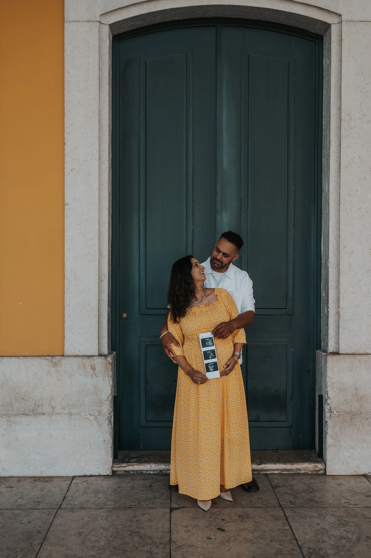 The expectant parents standing close together with the ultrasound photographs in the mother’s hands during their family and maternity photoshoot in Lisbon.
