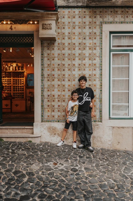 The children together beside the patterned tiles | Lisbon family photoshoot The two children standing together beside a colourful patterned tile wall during their family photoshoot in Lisbon.