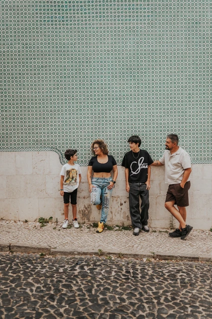A wide family portrait against the green tiles | Lisbon family photoshoot The family standing side by side along a green patterned tile wall during their family photoshoot in Lisbon.