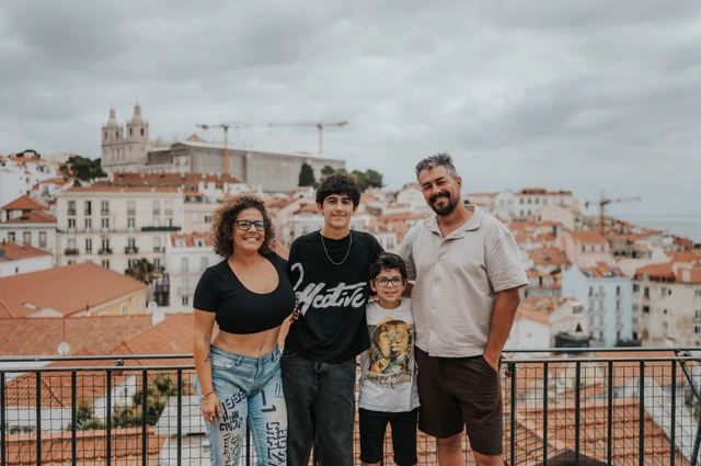 The family of four standing beside the viewpoint railing with Lisbon’s rooftops behind them during their family photoshoot in Lisbon.