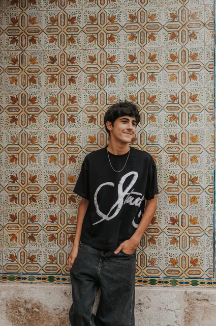 An individual portrait against Alfama’s tiles | Lisbon family photoshoot The older child standing beside the colourful patterned tile wall during their family photoshoot in Lisbon.