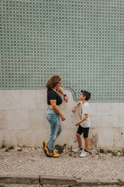 A parent-and-child moment beside the tiles | Lisbon family photoshoot A parent smiling with the younger child beside the green patterned tile wall during their family photoshoot in Lisbon.