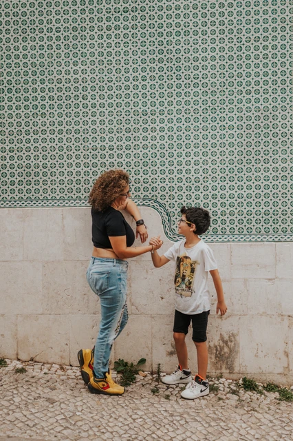 A parent-and-child moment beside the tiles | Lisbon family photoshoot A parent smiling with the younger child beside the green patterned tile wall during their family photoshoot in Lisbon.