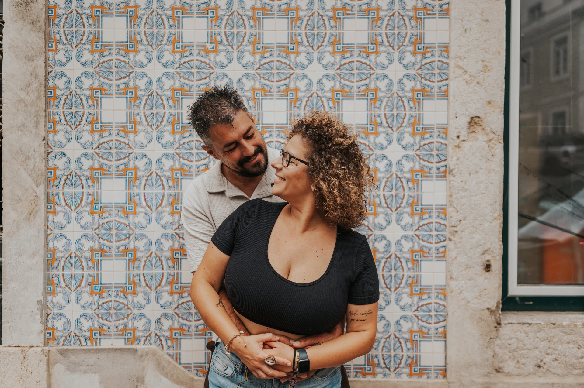 An embrace beside Alfama’s patterned tiles | Lisbon family photoshoot The parents embracing and looking at each other against a patterned tile wall during their family photoshoot in Lisbon.