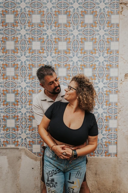 An embrace beside Alfama’s patterned tiles | Lisbon family photoshoot The parents embracing and looking at each other against a patterned tile wall during their family photoshoot in Lisbon.