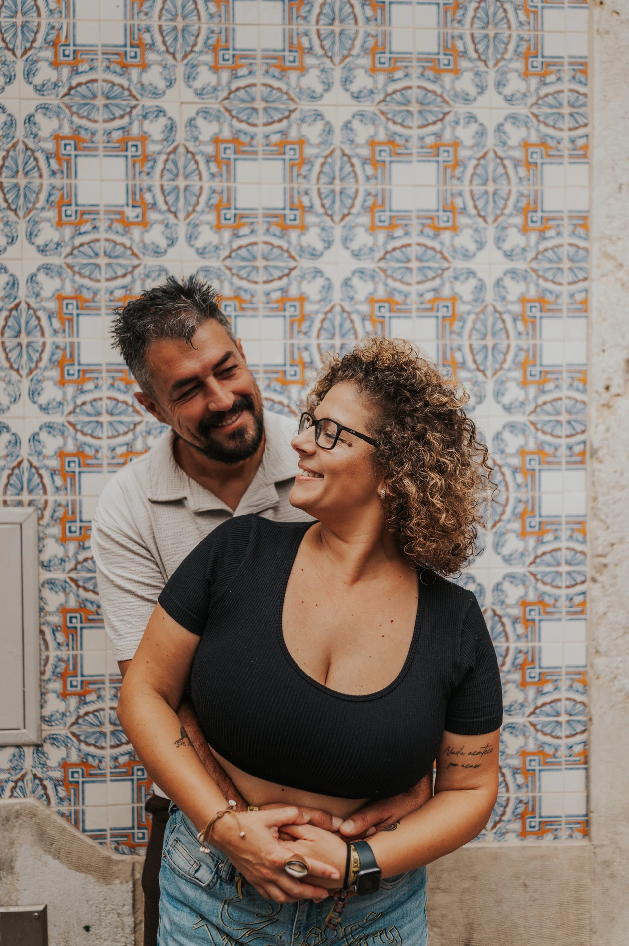 The parents embracing and looking at each other against a patterned tile wall during their family photoshoot in Lisbon.