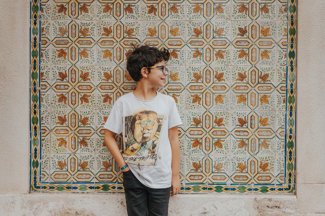 An individual portrait beside the patterned tiles | Lisbon family photoshoot The younger child standing in front of a colourful patterned tile panel during their family photoshoot in Lisbon.