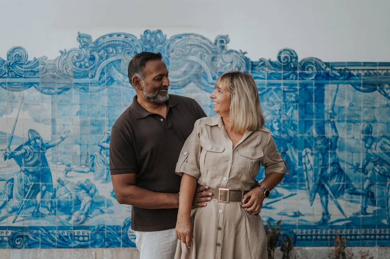 A close portrait against the blue tiles | Lisbon couple photoshoot The couple standing close together and smiling at each other in front of the blue tile panel during their couple photoshoot in Lisbon.