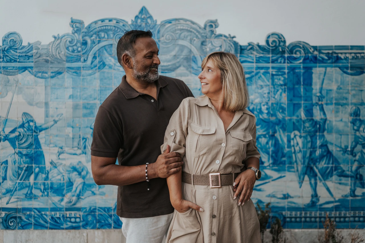 A close portrait against the blue tiles | Lisbon couple photoshoot The couple standing close together and smiling at each other in front of the blue tile panel during their couple photoshoot in Lisbon.
