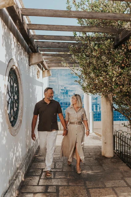 The couple walking hand in hand beneath the pergola at Miradouro de Santa Luzia during their couple photoshoot in Lisbon.